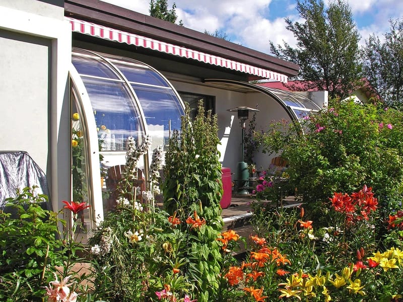 Runde, gewölbte Terrassenüberdachung aus Aluminium und Polycarbonat an einem Wohnhaus