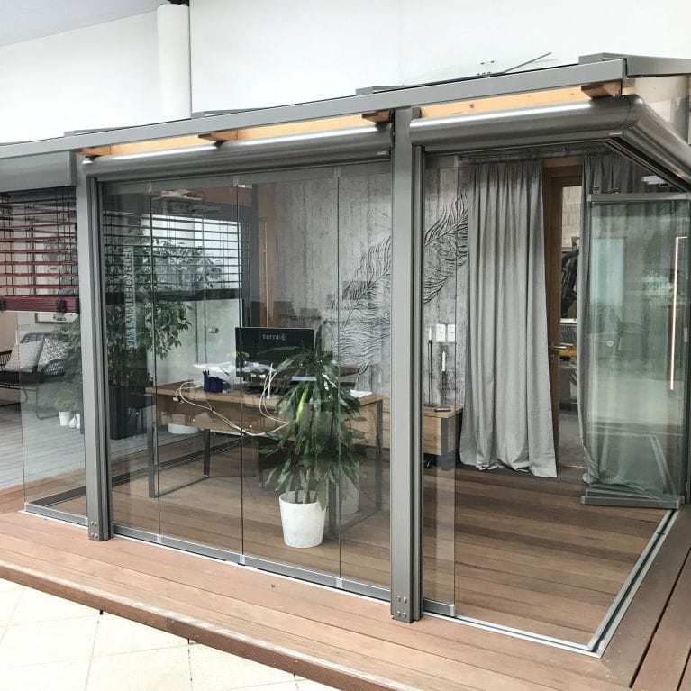Musterausstellung mit klassischer Terrassenüberdachung und weißen Fensterelementen