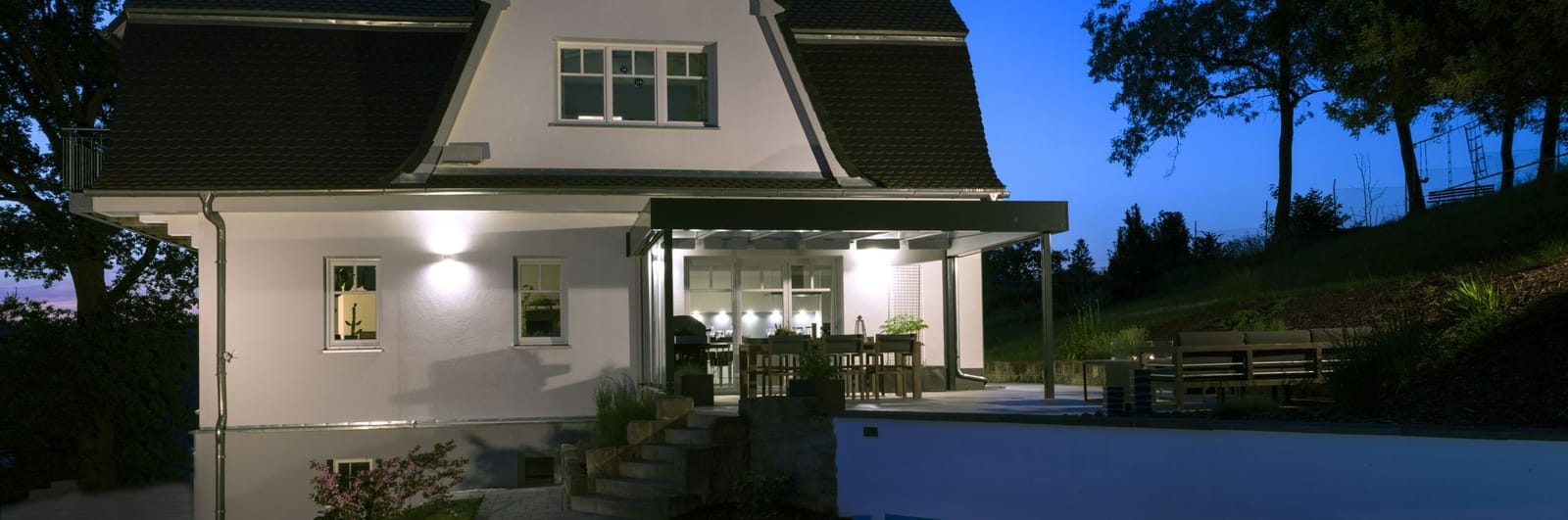 Offene Terrassenüberdachung über einer gepflasterten Terrasse mit Loungemöbeln