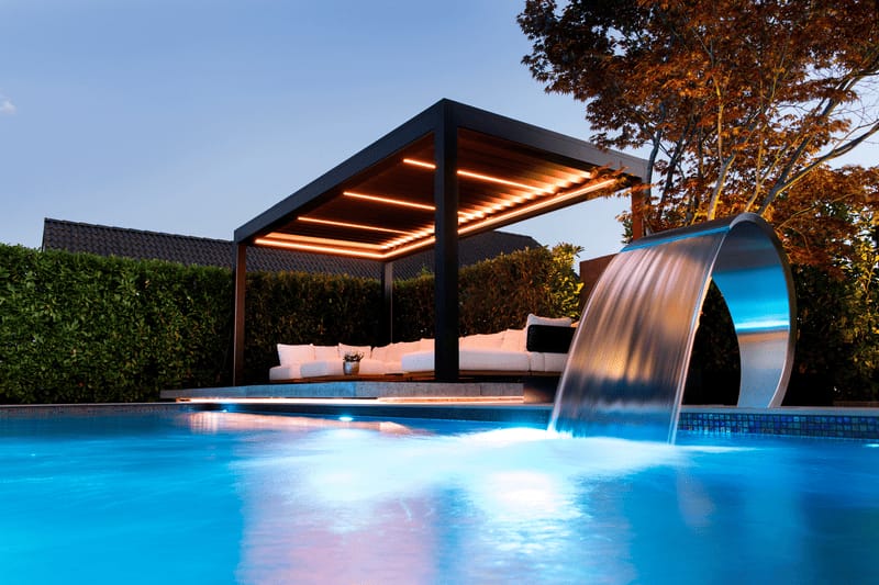Terrasse mit Pool und geöffnetem Lamellendach in der Abenddämmerung, moderne Loungemöbel am Wasser