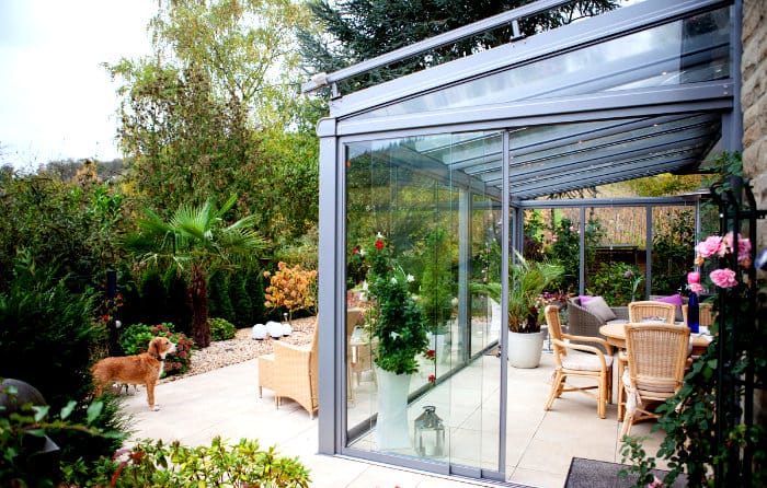 Kalverkamp Glashaus-Wintergarten mit Blick auf die Terrasse und einen Hund im Garten, Referenzprojekt Lieser