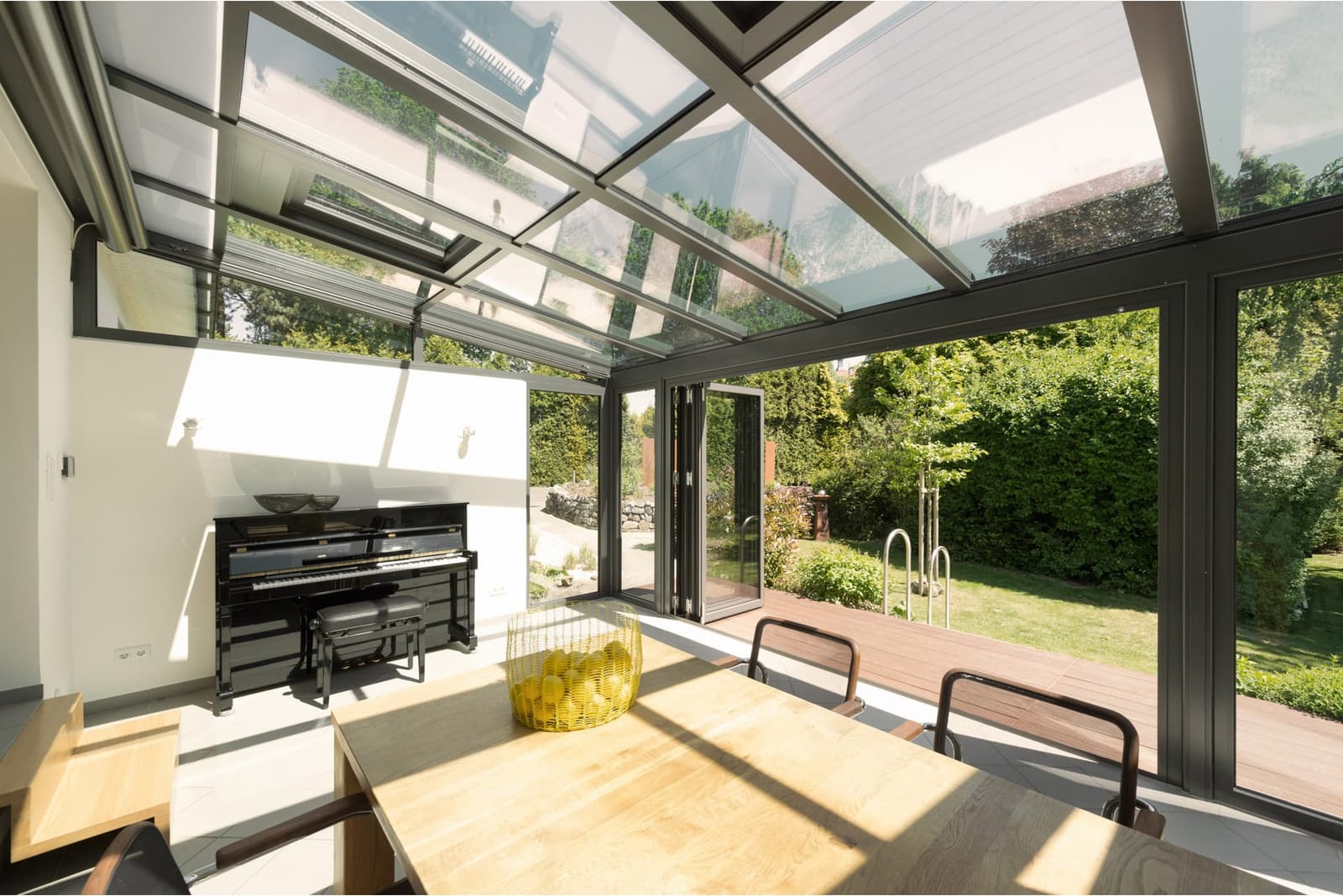 Wohnwintergarten von innen mit Glasdach, Esstisch und Blick auf die Terrasse (Kalverkamp)