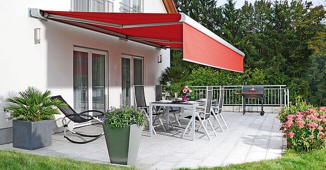 Große Kassettenmarkise mit weit ausgefahrenem Tuch über mehreren Tischen auf einer Restaurantterrasse