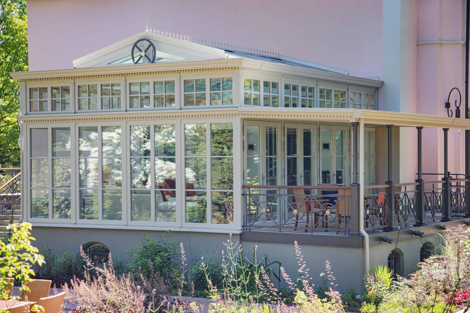 Klassizistische Orangerie mit weißem Gesims und Zierelementen an einem herrschaftlichen Wohnhaus, Gartenblick