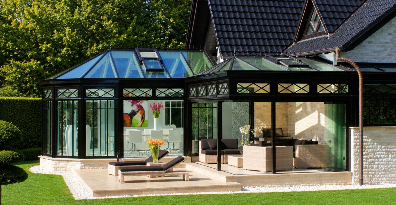 Klassischer Wintergarten mit weißem Sprossenwerk, Zierfirst und Walmdach an einem Wohnhaus