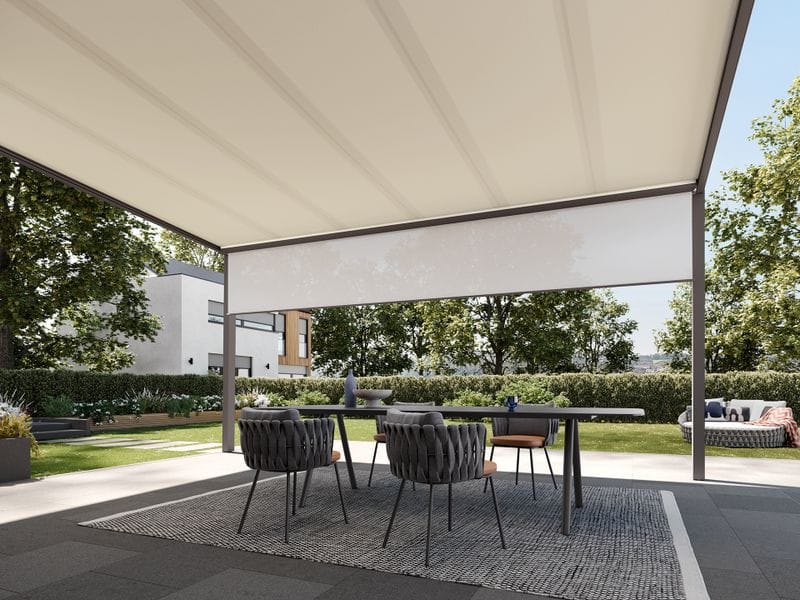 Ausgefahrene Kassettenmarkise über einer Terrasse bei Abendlicht, gemütliche Sitzgruppe darunter