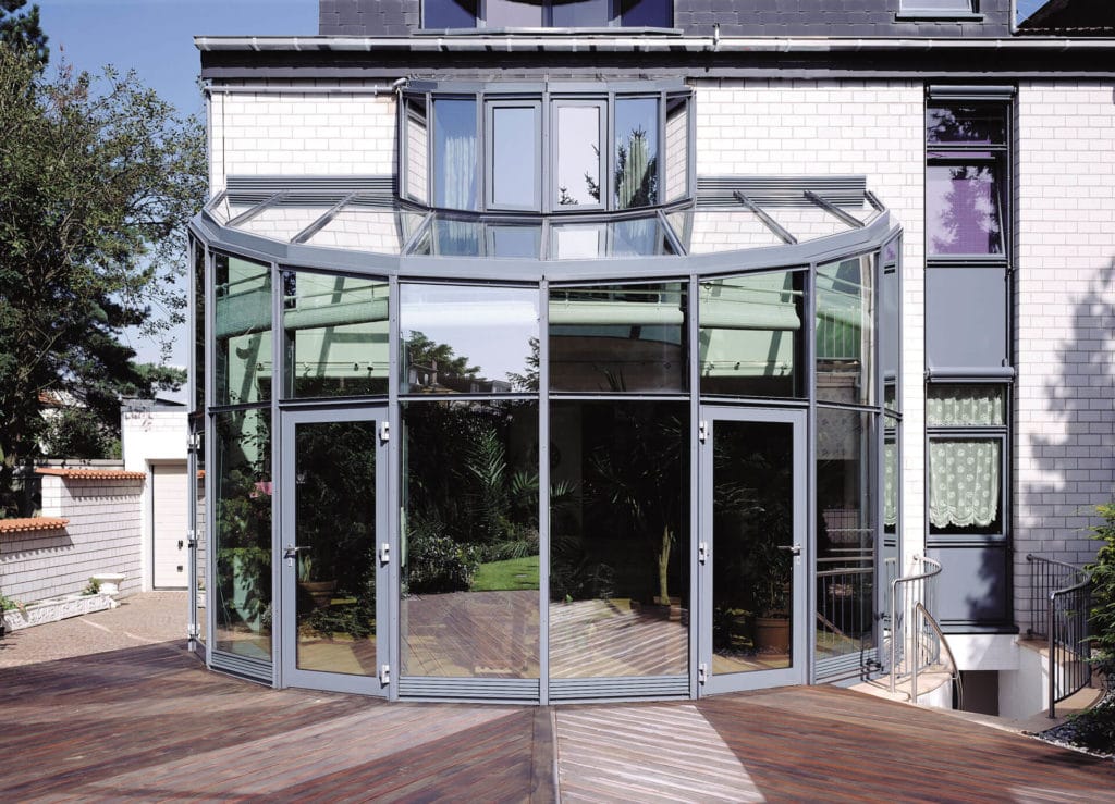 Martin Wintergärten Aluminium-Wintergarten mit geschwungener Glasfassade, Außenansicht mit Terrassenzugang