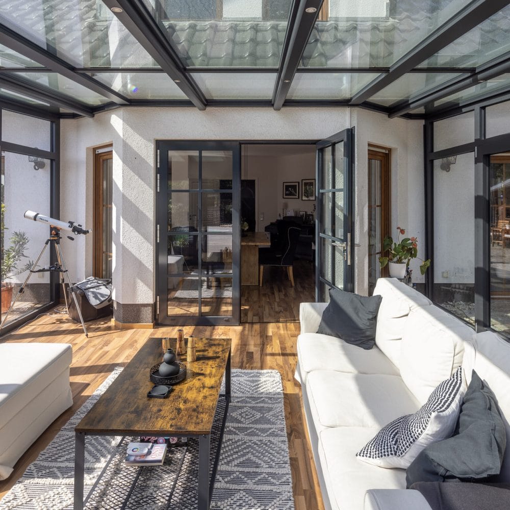 masson Warmwintergarten von innen mit dunklem Aluminiumrahmen, Glasdach und Loungebereich