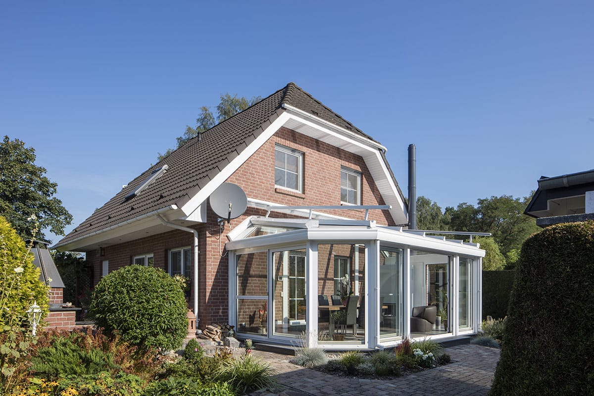 masson Warmwintergarten mit weißem Aluminiumrahmen und Walmdach an einem Backsteinhaus