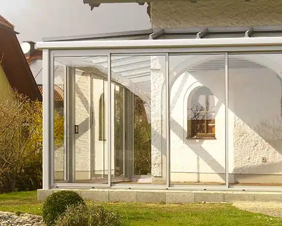 Sommergarten mit Aluminium-Schiebeverglasung an einem Einfamilienhaus mit weißer Putzfassade (Fenster Schmidinger, Oberösterreich)