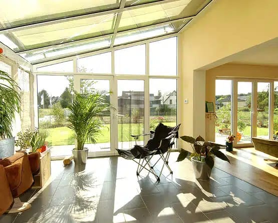 Möblierter Wohnwintergarten mit Glasdach, Pflanzen und großer Fensterfront von innen (Fenster Schmidinger)