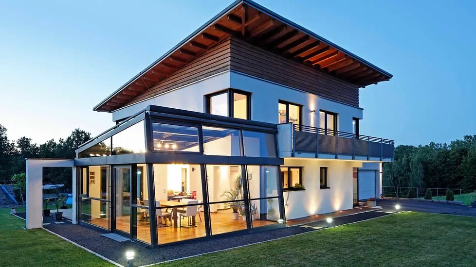 Einfamilienhaus mit integriertem Glasanbau aus Schüco Aluminium-Profilen, Abendstimmung mit beleuchtetem Innenraum