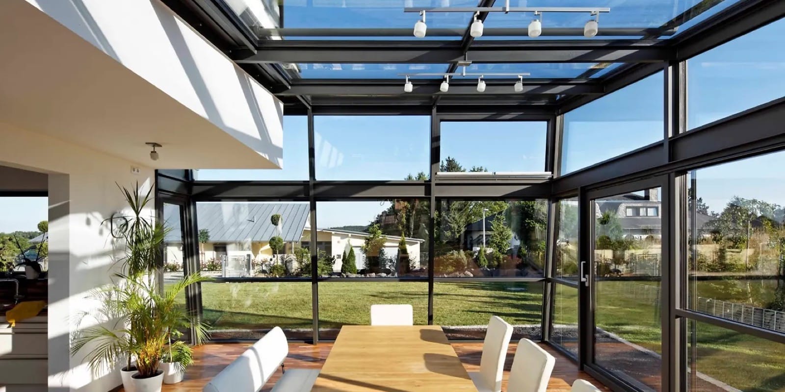 Wohnwintergarten mit schlanken dunklen Aluminiumprofilen und Glasdach von innen mit Esstisch