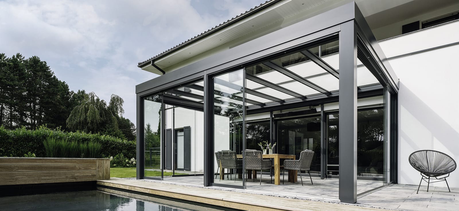 Aluminium-Terrassendach mit Glasdach und rahmenlosen Schiebeelementen an einem Pool