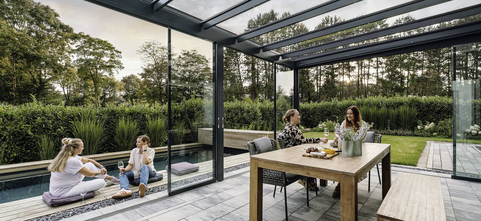 Menschen entspannen an einem Solarlux SDL Acubis Terrassendach am Pool, Abendlicht