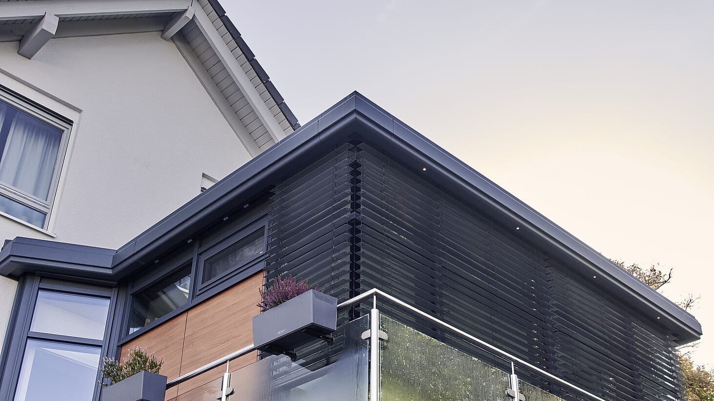 Terrassenanbau mit Lamellen-Sonnenschutz und Glasbrüstung am Haus