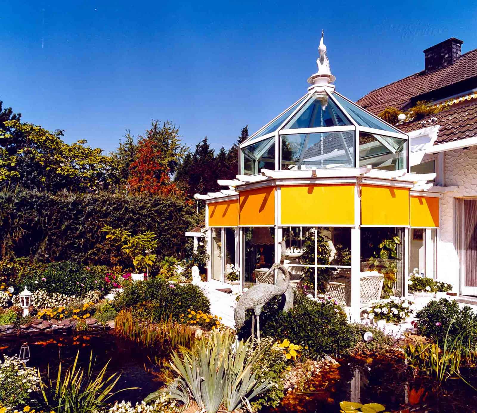 Sunshine DecoArt Wintergarten mit achteckigem Türmchendach und orangefarbener Markise bei Tag
