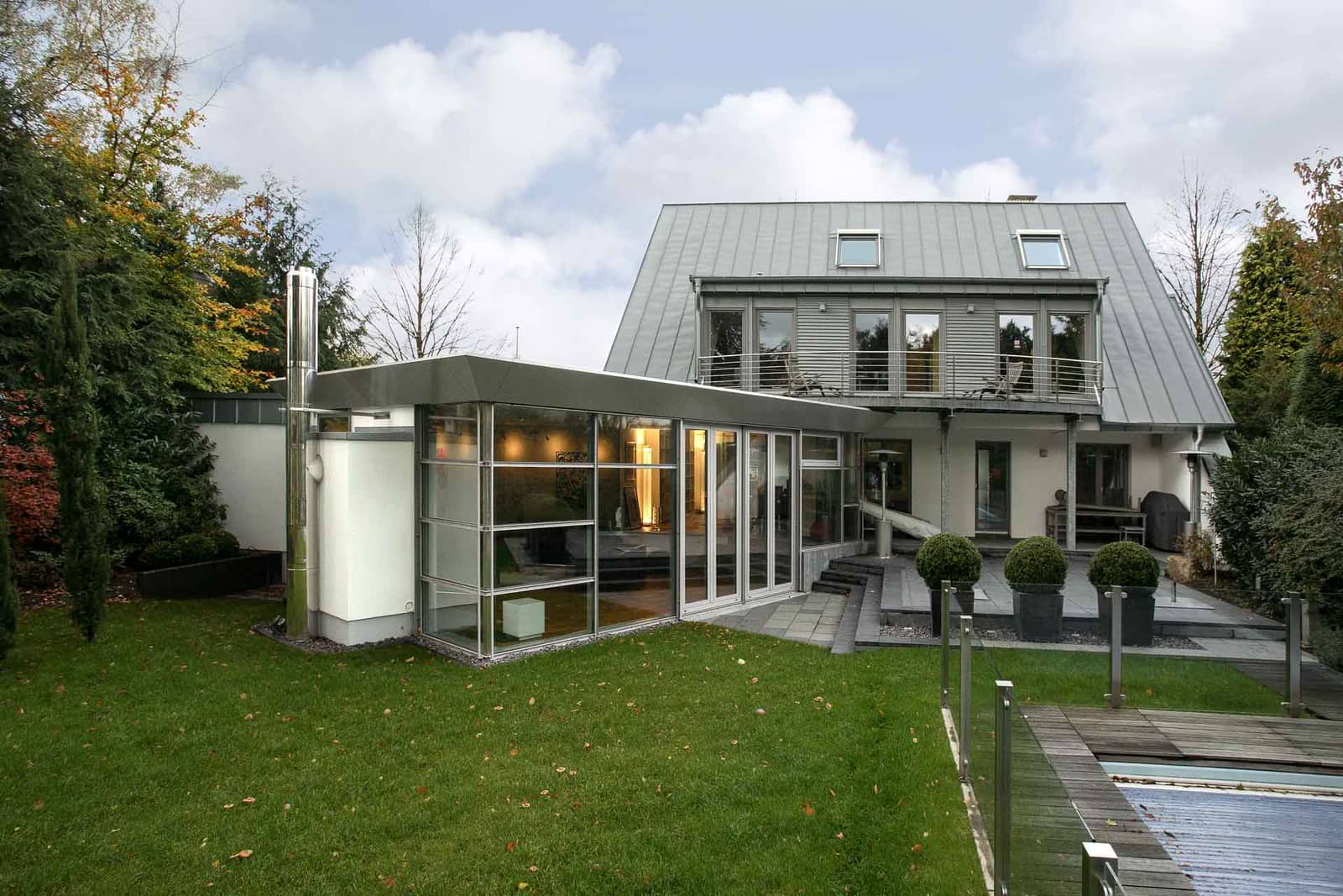 Moderner Flachdach-Wintergarten aus Aluminium mit großer Glasfront an einem Haus mit Garten und Pool