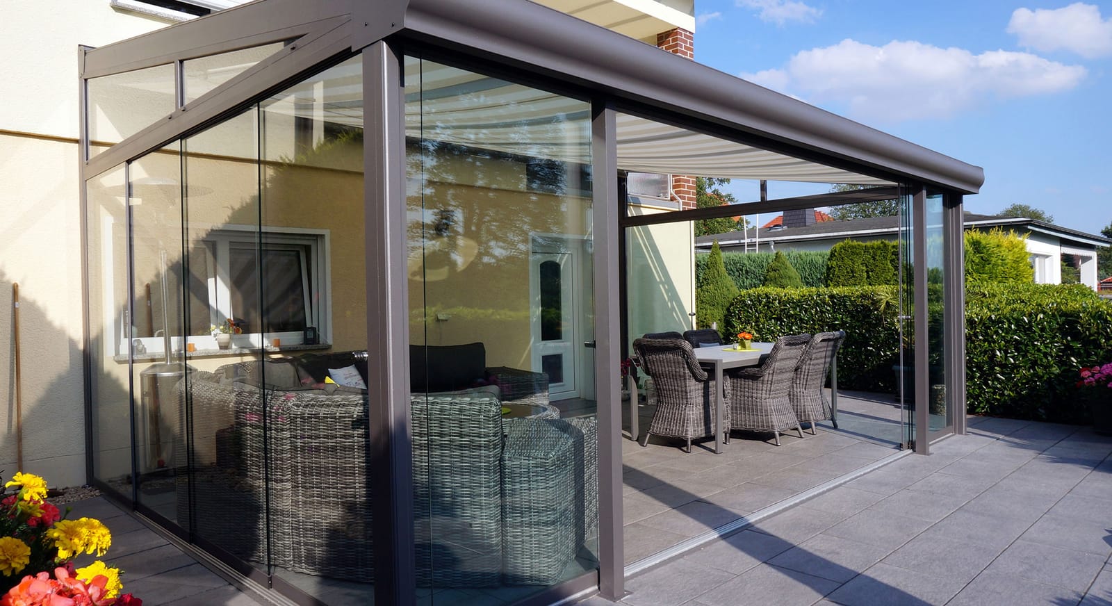 Wipro Diafano Terrassendach mit Satteldach und Markise seitlich an einem Einfamilienhaus